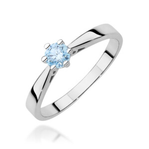 Kihlasõrmus. Silver ring with a light blue round-cut gemstone held by four prongs, photographed at an angle against a white background.