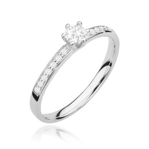 Kihlasõrmus. White metal engagement ring with a round center diamond in prongs and smaller diamonds along the band (solitaire with pavé set stones).