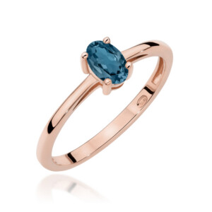 Kihlasõrmus. Rose gold ring with an oval blue gemstone held by four prongs on a simple band and white background.